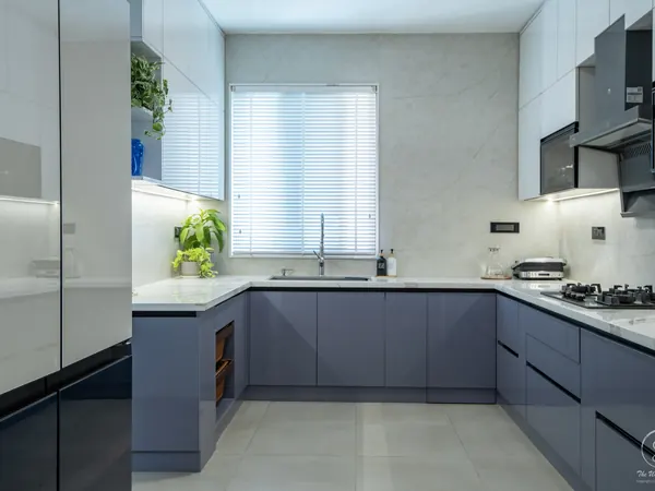 Kitchen with grey-blue lower cabinets, white uppers and a window over the sink