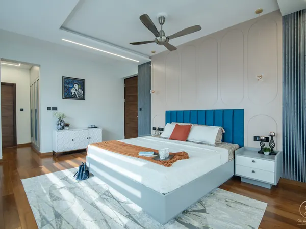 Bedroom with a blue panelled headboard, wood floor and a slatted wall