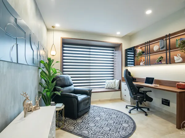 Study with a lit wall shelf, a wooden desk and a leather recliner by the window