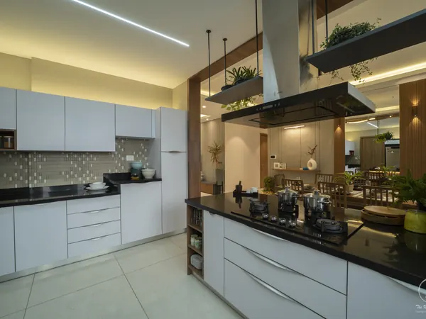 White kitchen with a black counter, open shelves and a hood over the island