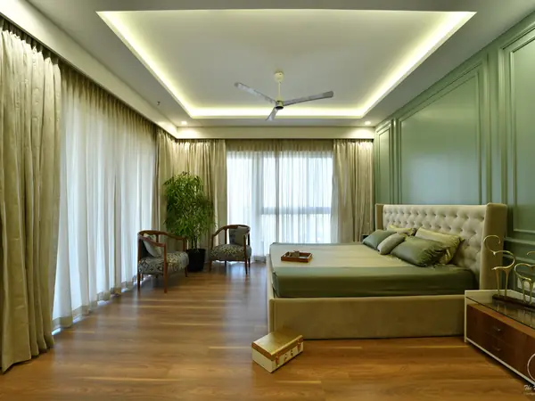 Sage green bedroom with panelled walls and a cove-lit ceiling