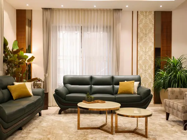 Formal living room with dark leather sofas and gold-edged tables