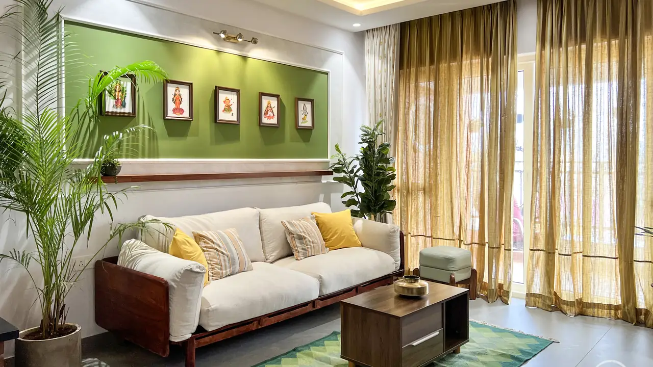 Living room with a green feature wall, framed art and a linen sofa