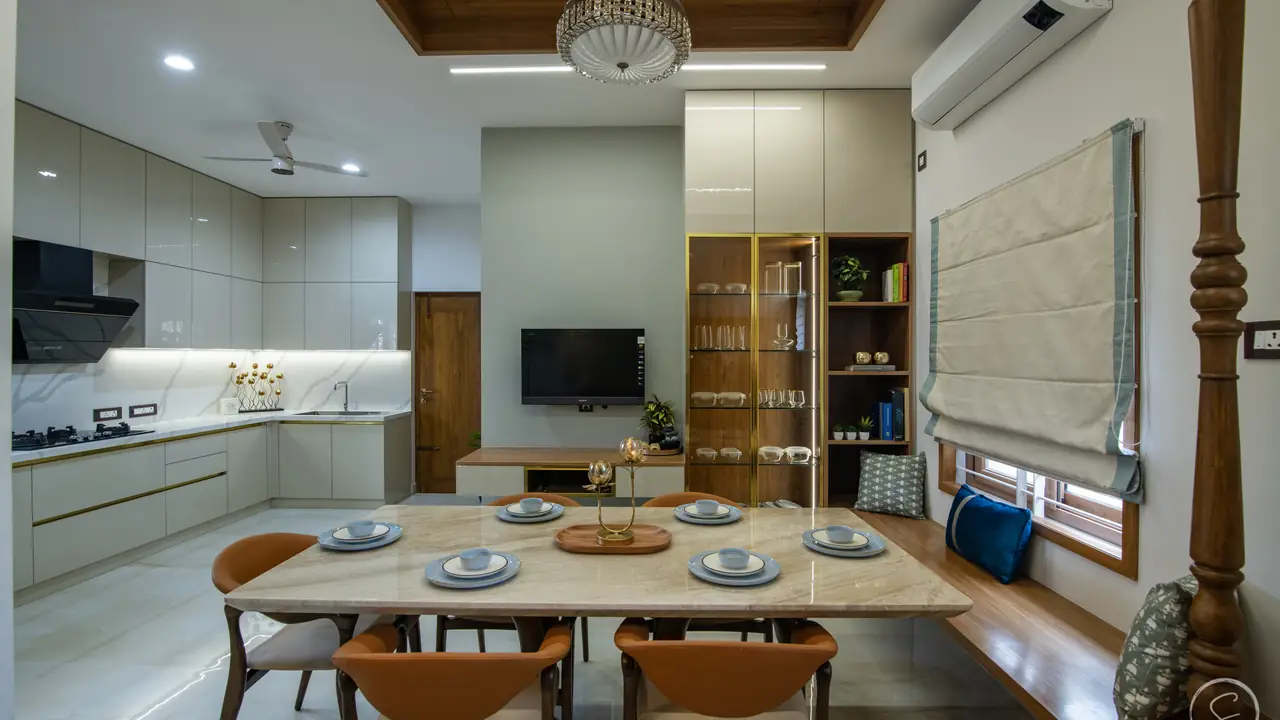 Dining table for eight beside a light grey kitchen with a glass-fronted crockery unit