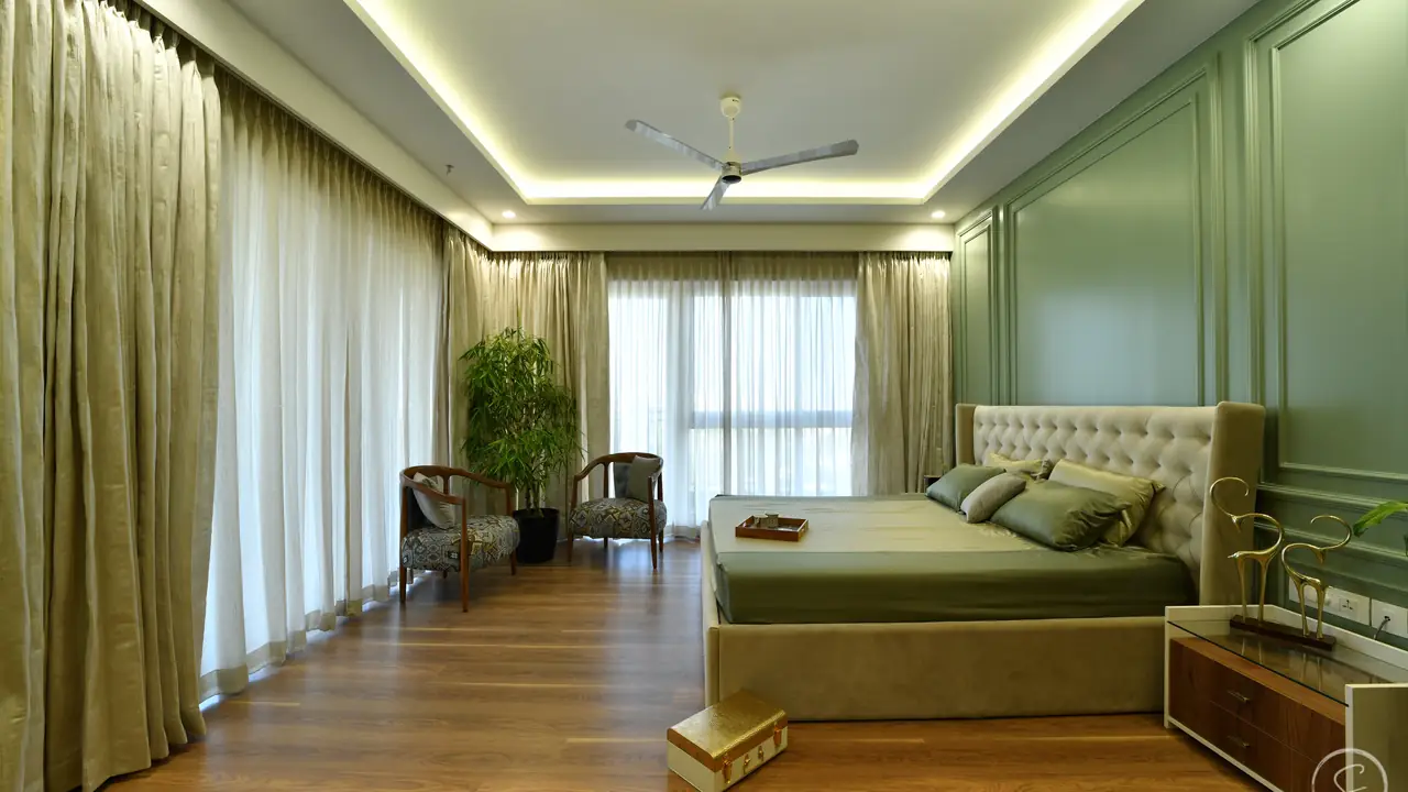 Sage green bedroom with panelled walls, oak floor and a cove-lit ceiling